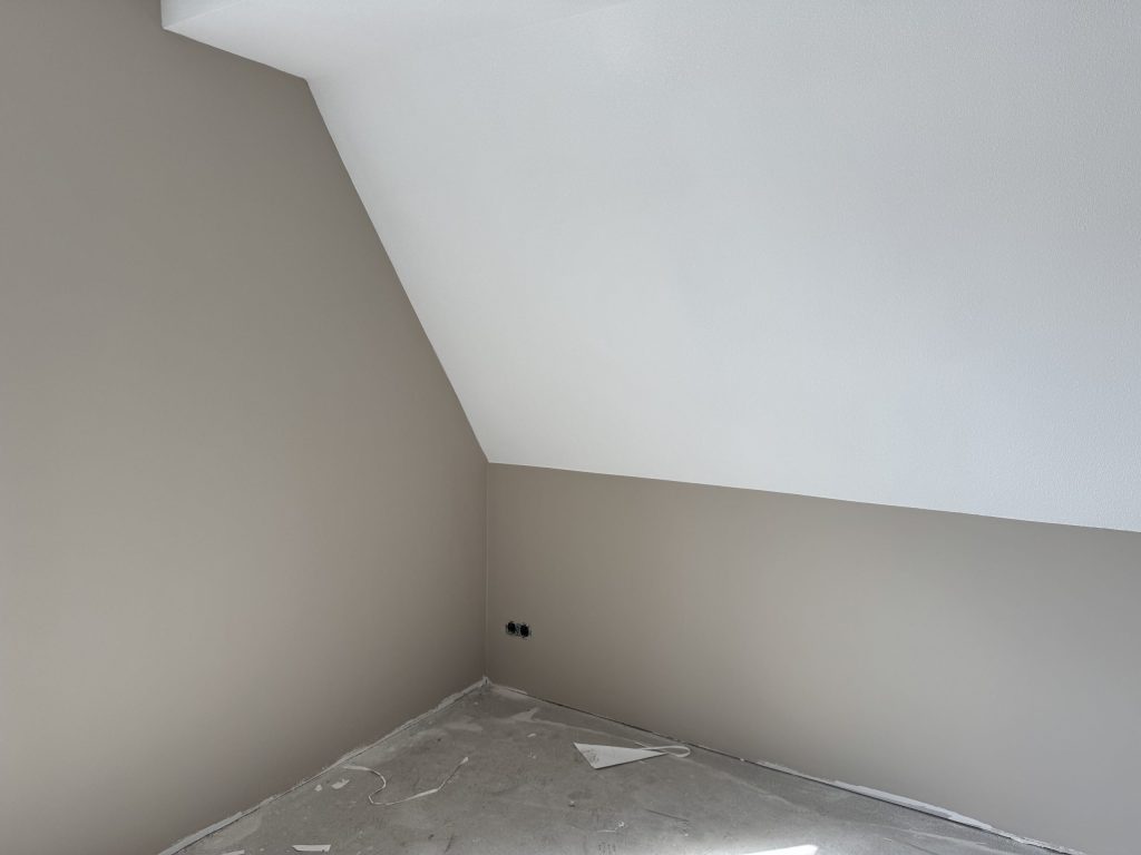 Zolderkamer met een schuine wand, muren in warm grijs en een wit dakvlak